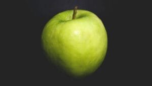 A fresh green apple on a black table.