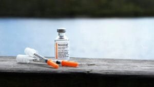 An orange and white plastic bottle on a brown wooden table.