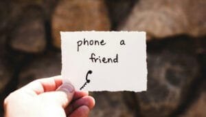 A person holding a piece of paper with "Phone a Friend" written on it.