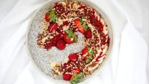 Red and white fruit salad in a white ceramic bowl.