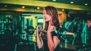 A woman lifting a black and gray barbell.